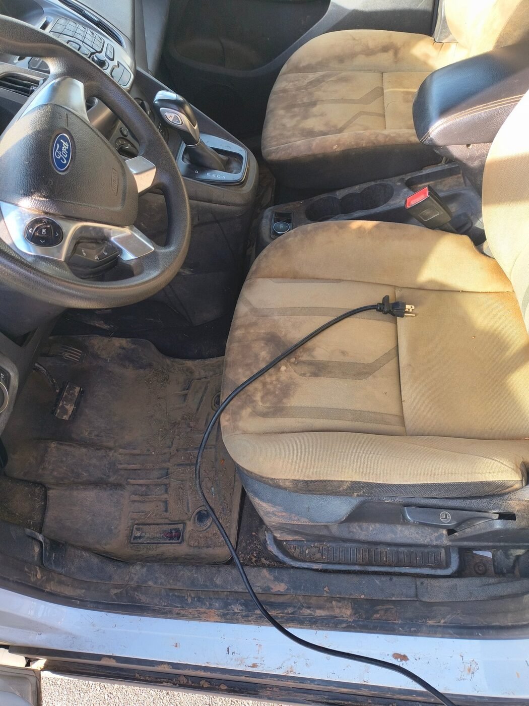 Before: Ford Transit Connect work van driver and passenger seats heavily soiled, with a muddy floor mat and door sill, before a Gleam Team interior detail in Charlotte and Raleigh NC