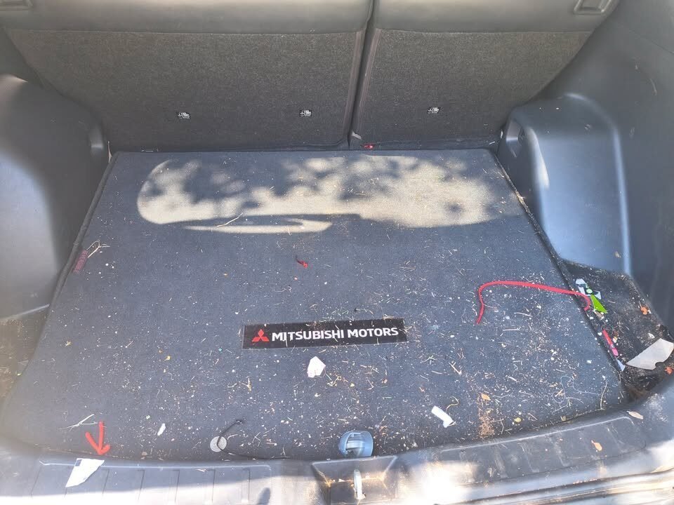 Before: Mitsubishi SUV cargo area carpet covered in debris, crumbs and trash before a Gleam Team interior detail in Charlotte and Raleigh NC